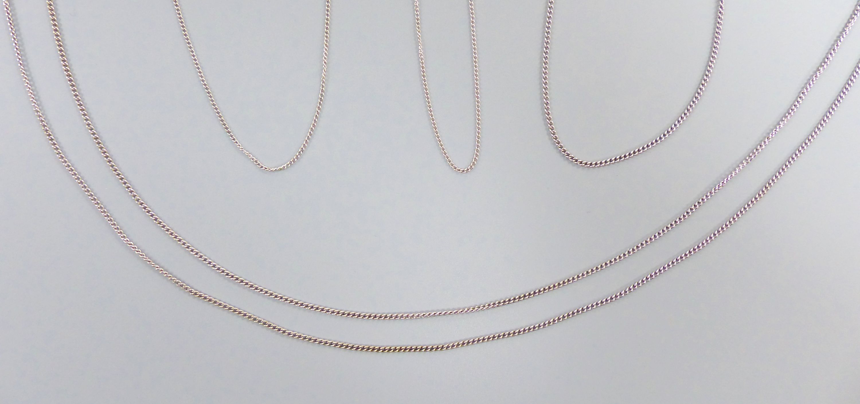 Four assorted white metal finelink chains, stamped 9ct,
